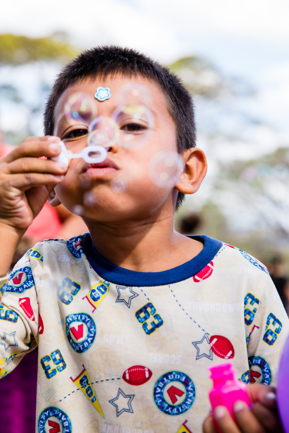 boy from Nicaragua playing with bubbles, blowing at camera