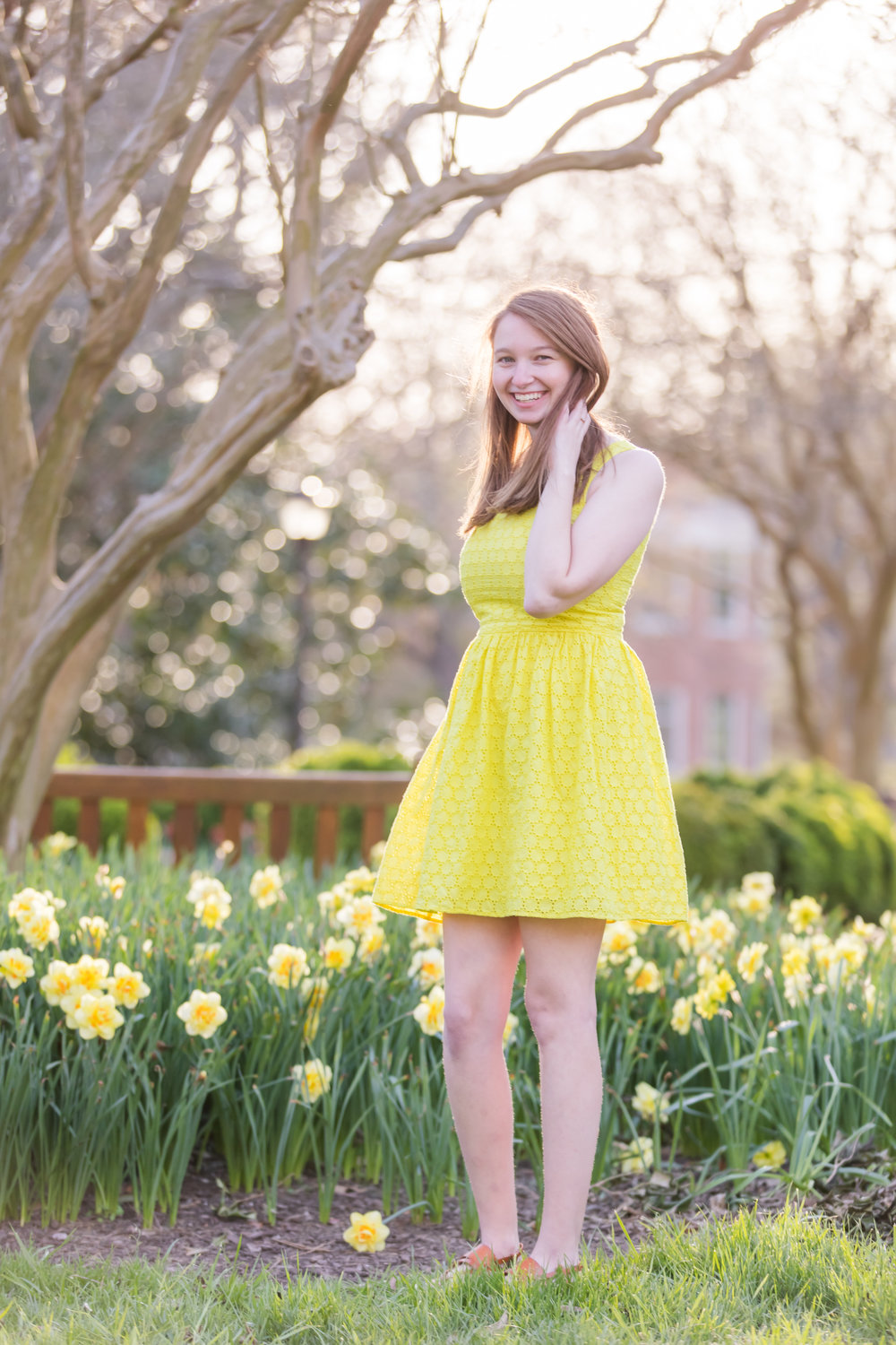 graduate in yellow dress with yellow flowers for spring senior portraits