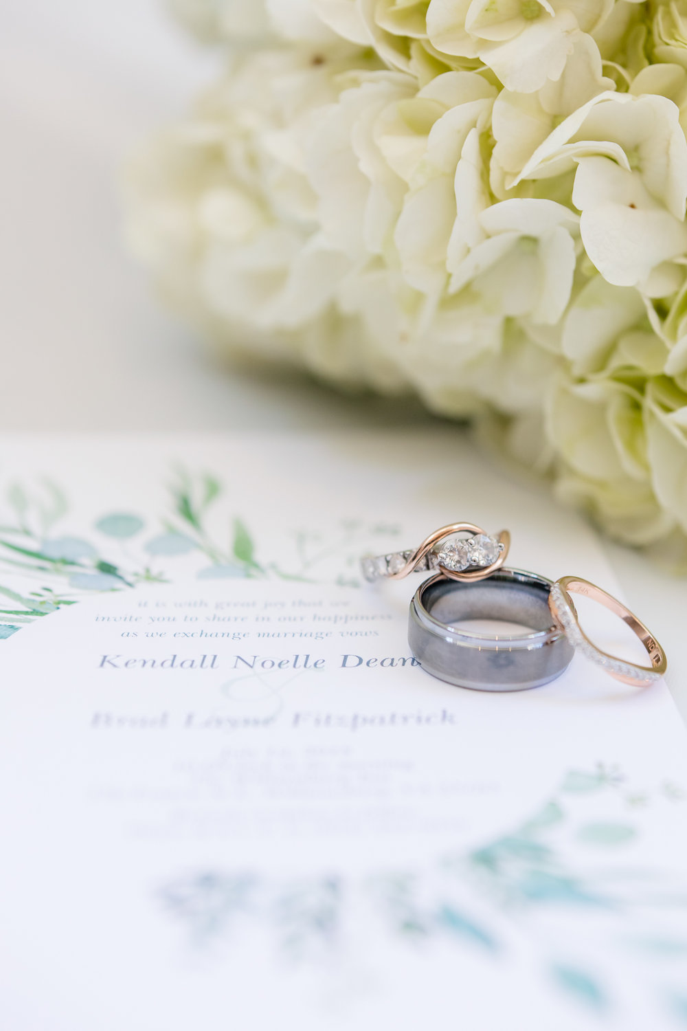 rings and invitation photo with florals in background