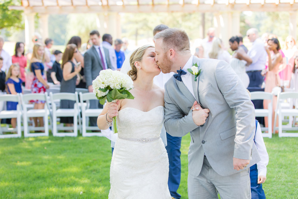 bride and groom grab a kiss after exiting wedding ceremony