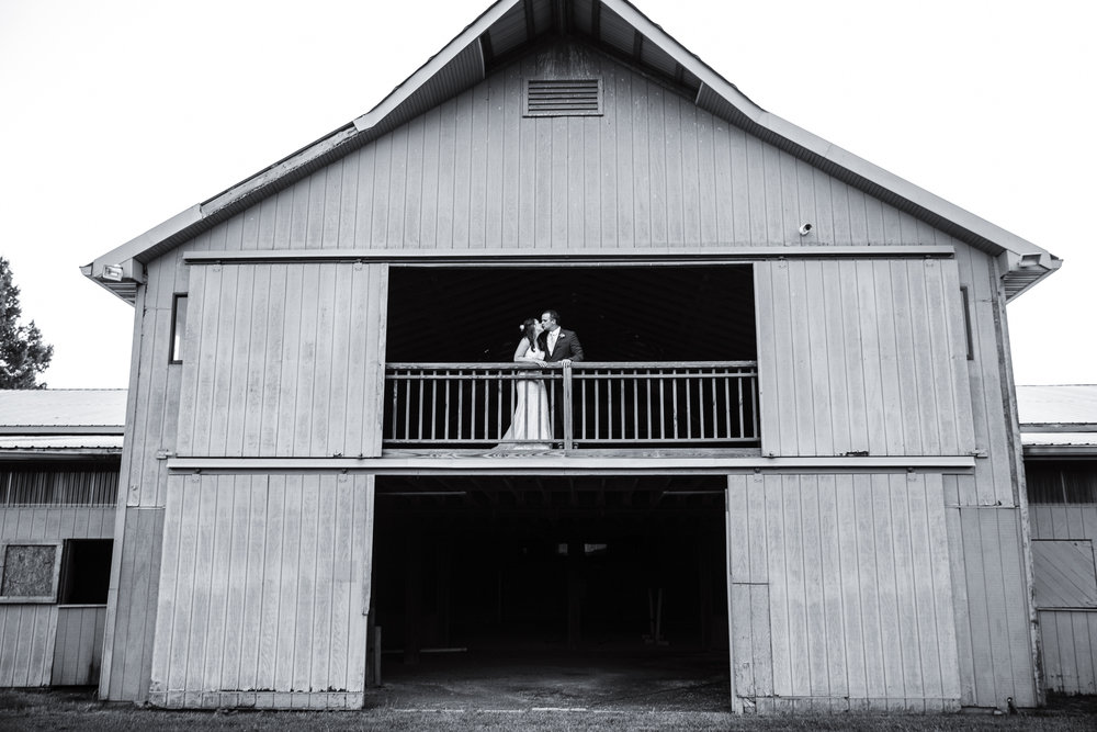 bride and groom kiss on barn balcony for Carlton Farms wedding