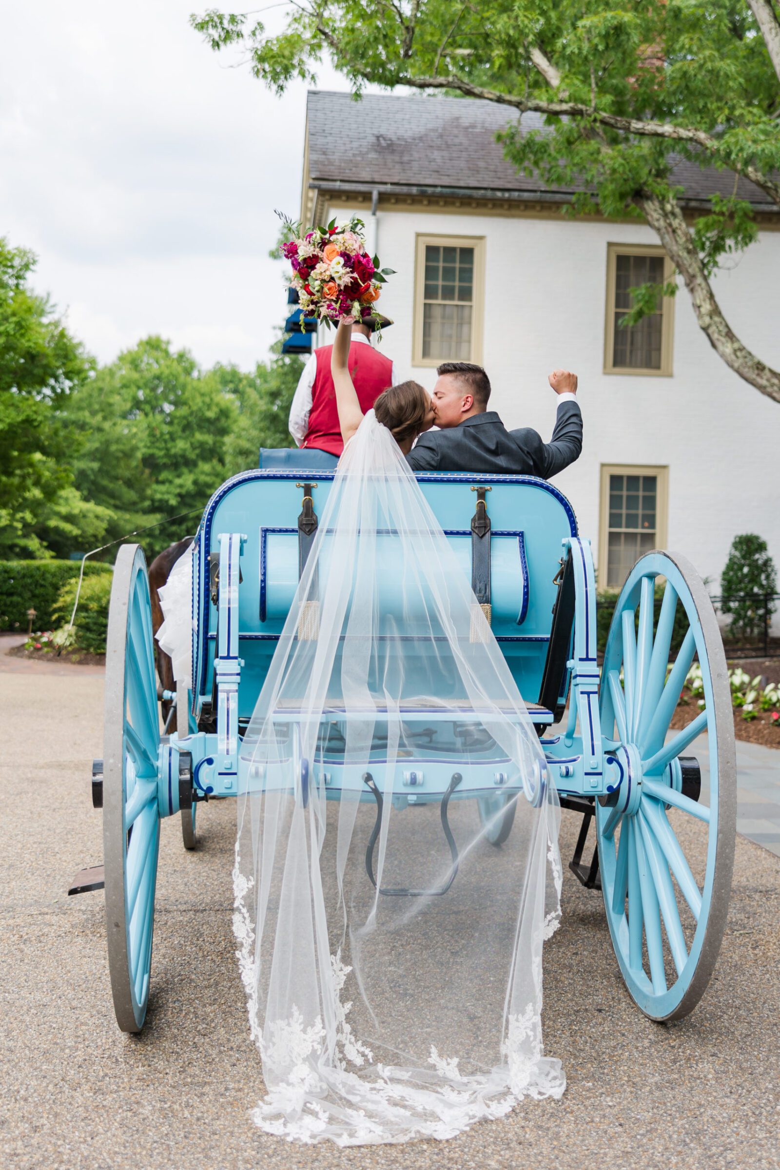 Celebration fist pump riding away on a horse and carriage after a Colonial Williamsburg Inn wedding
