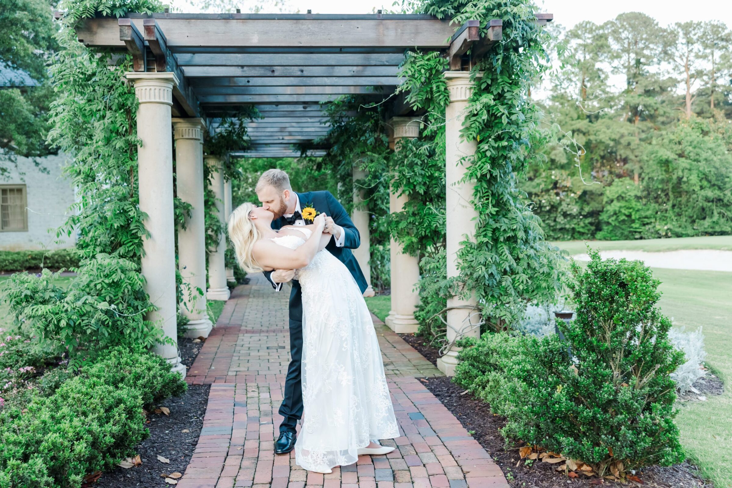 Groom dips bride for kiss under the trellis at their Colonial Williamsburg wedding with CW Resorts