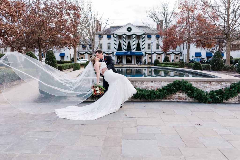 Bride and groom with veil kissing in front of the iconic Williamsburg Inn wedding venue 
