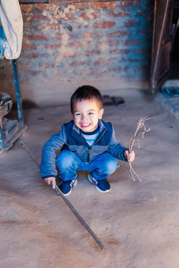 boy plays with sticks in village taken by India travel photography