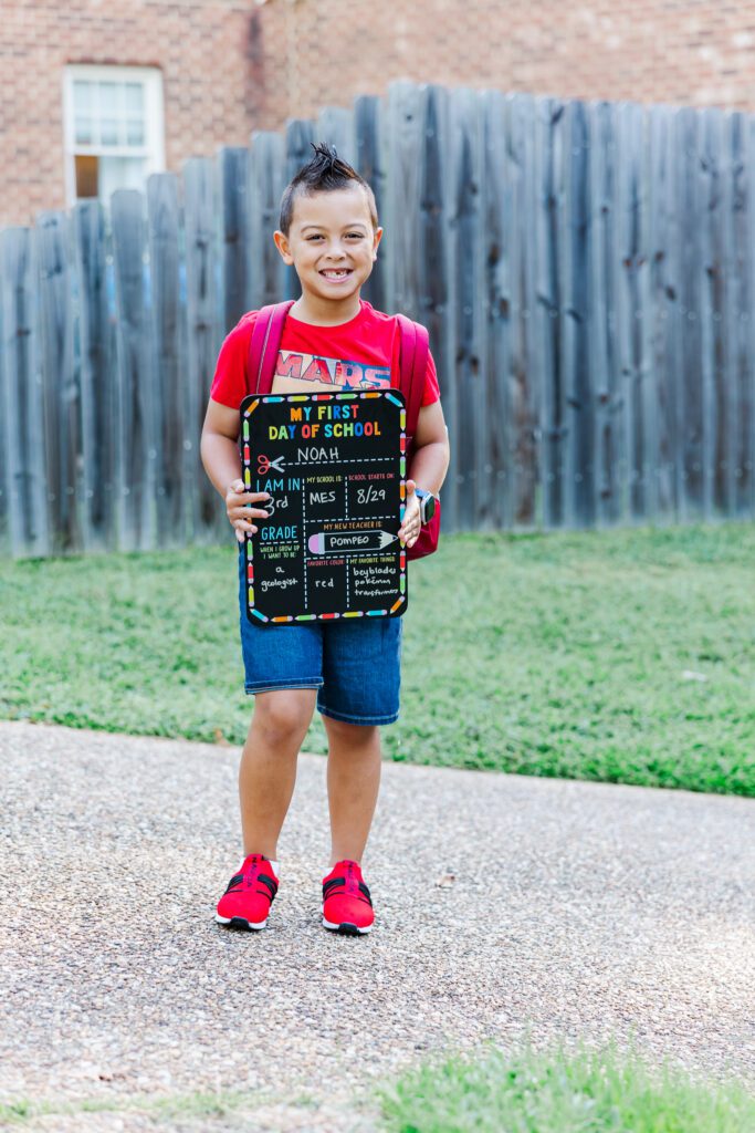 boy wearing red and holding back to school sign