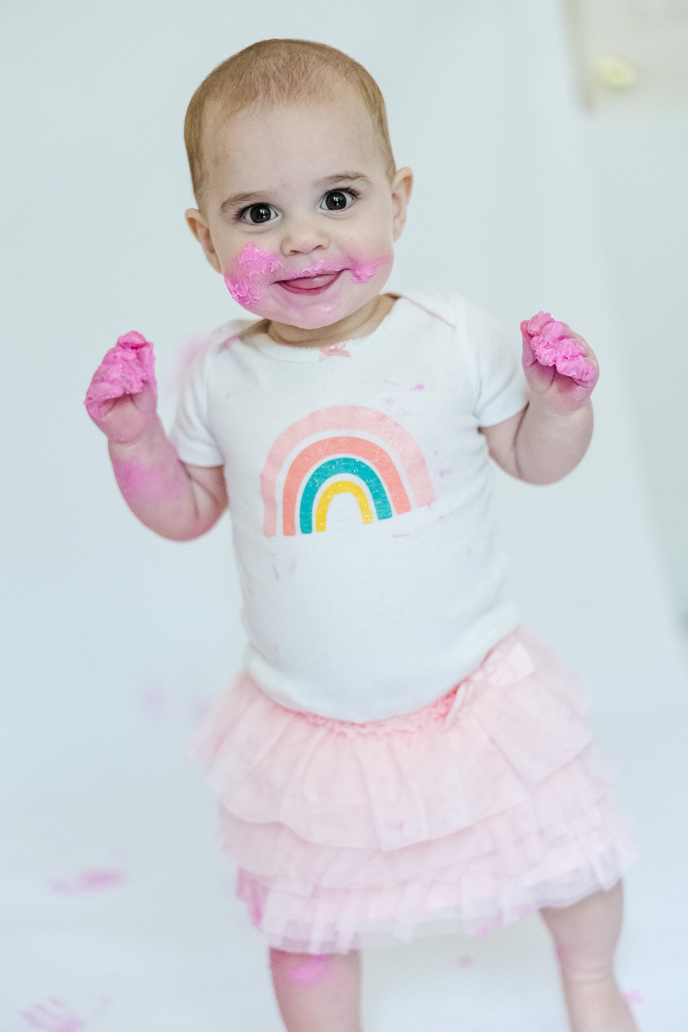 baby with pink icing and cake all over for first birthday pictures
