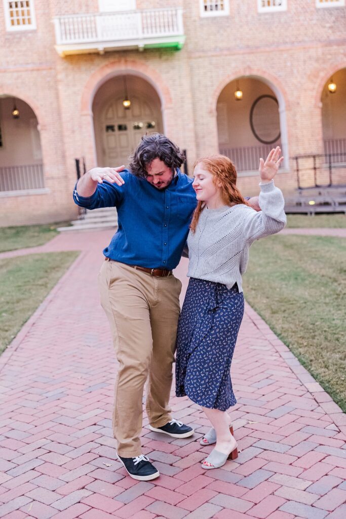 engaged couple dances in front of William & Mary Wren Building after surprise proposal