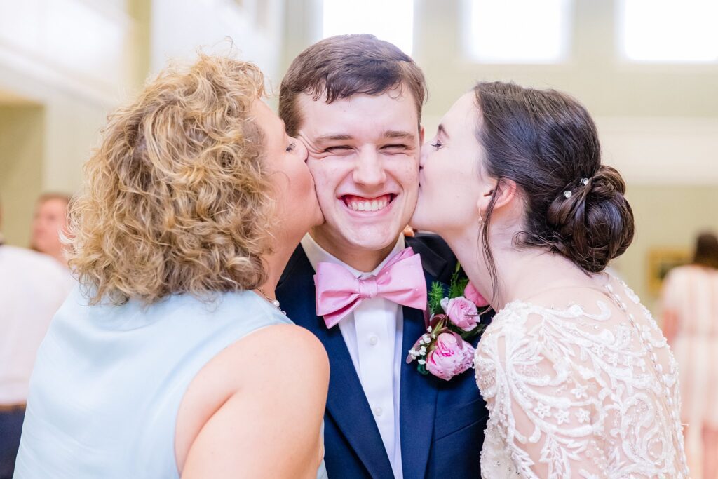 mother of groom and bride kiss groom on each cheek
