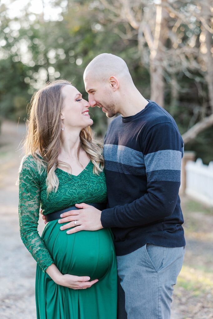 couple touches noses and smiles during maternity session by Colonial Williamsburg photographer