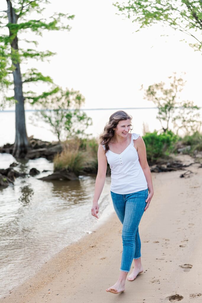 senior laughs while walking on beach for senior mini session in Williamsburg, VA