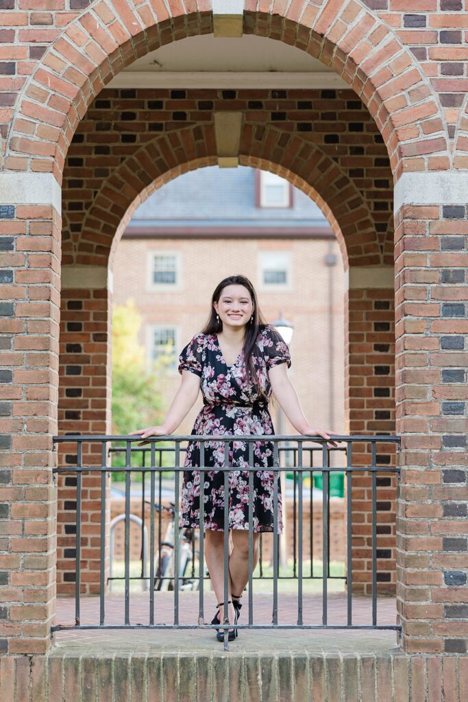 senior poses in arcs of brickwork on Old Campus side of William and Mary