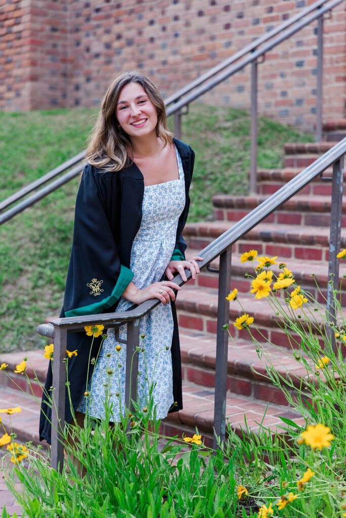 senior poses on stairs with yellow wildflowers from W&M Class of 2023