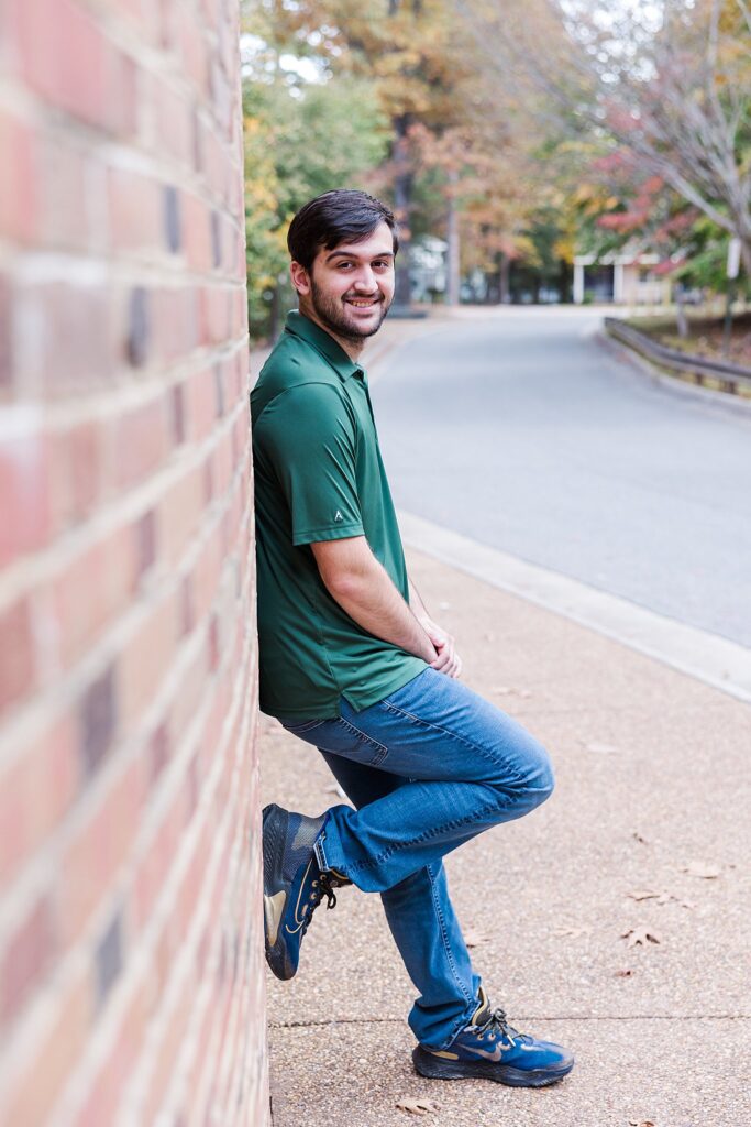 senior leaning on brick wall for iconic image if you're looking for where to take photos at William & Mary