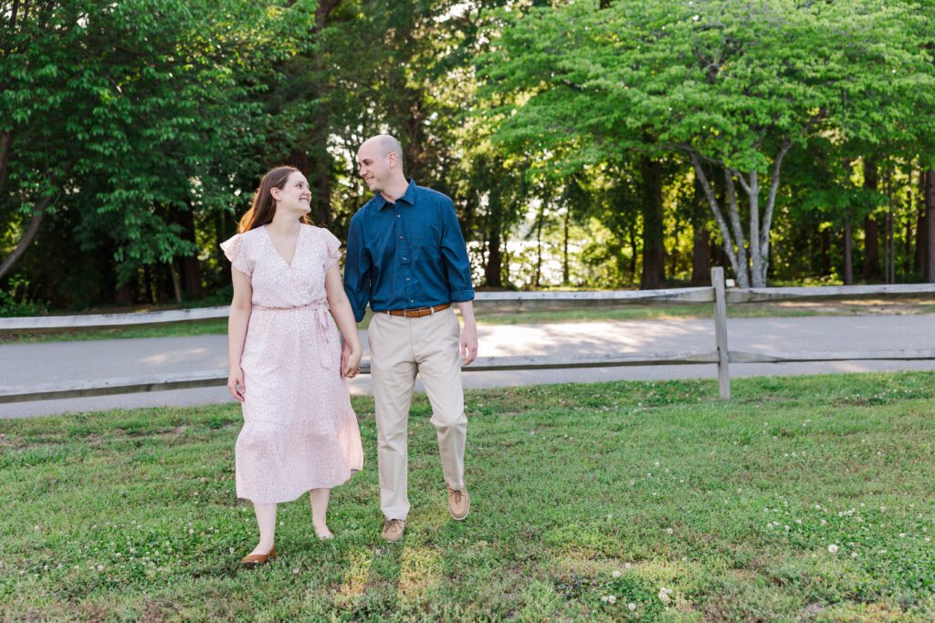 couple walks holding hands and looking at each other during family photos at Chickahominy