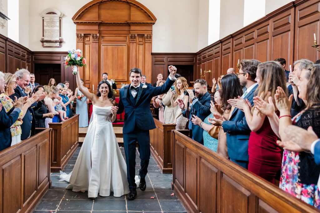 couple celebrates walking down the aisle in the Wren Chapel 
