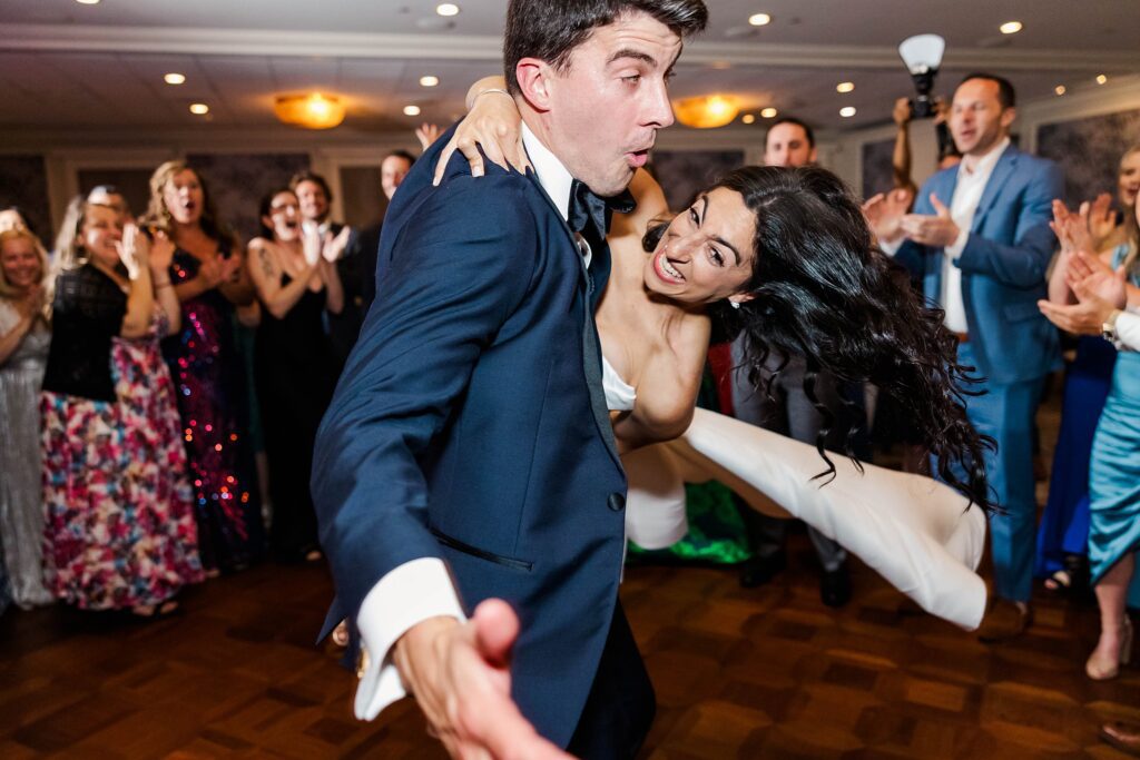 groom spins bride on dance floor for action photo