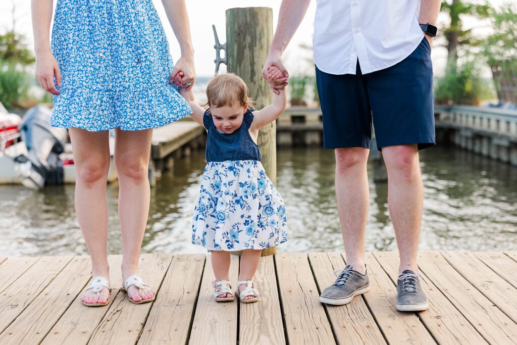 toddler holding parents hands at family mini session on the James River