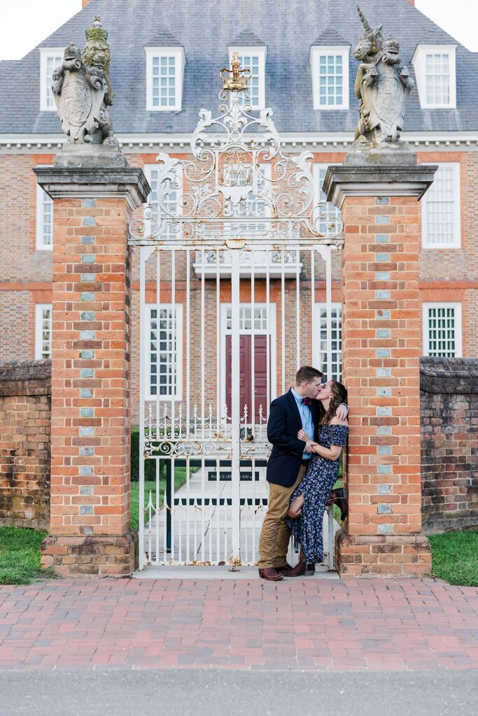 engaged couple leaning in front of Colonial Williamsburg Governor's Palace at fall engagement session
