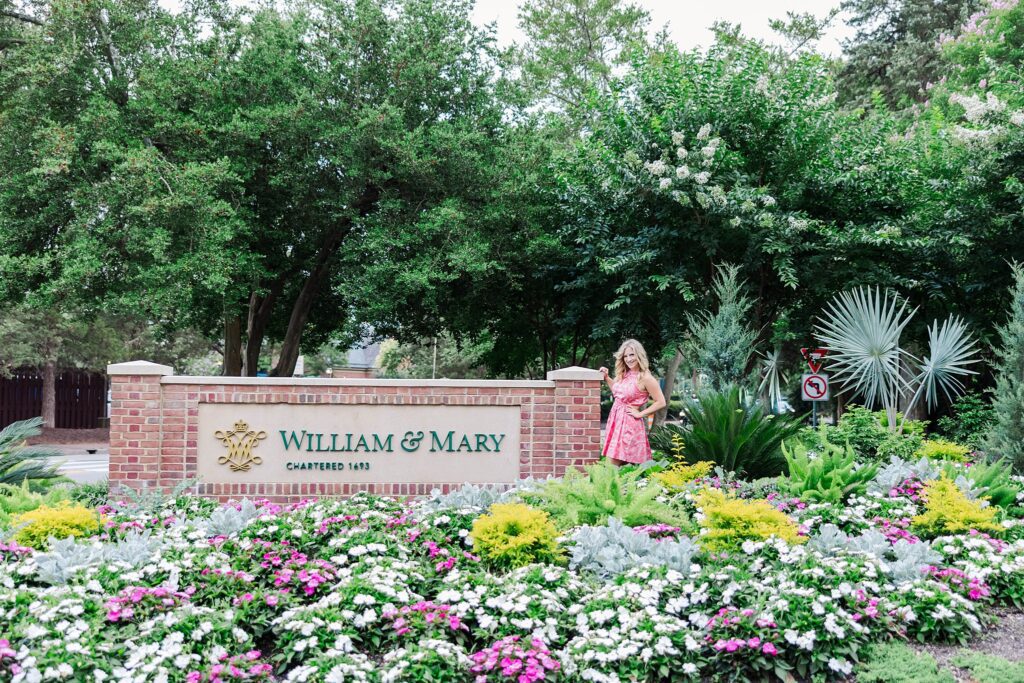 Senior in pink dress poses by sign for graduation pictures from William & Mary Law School 