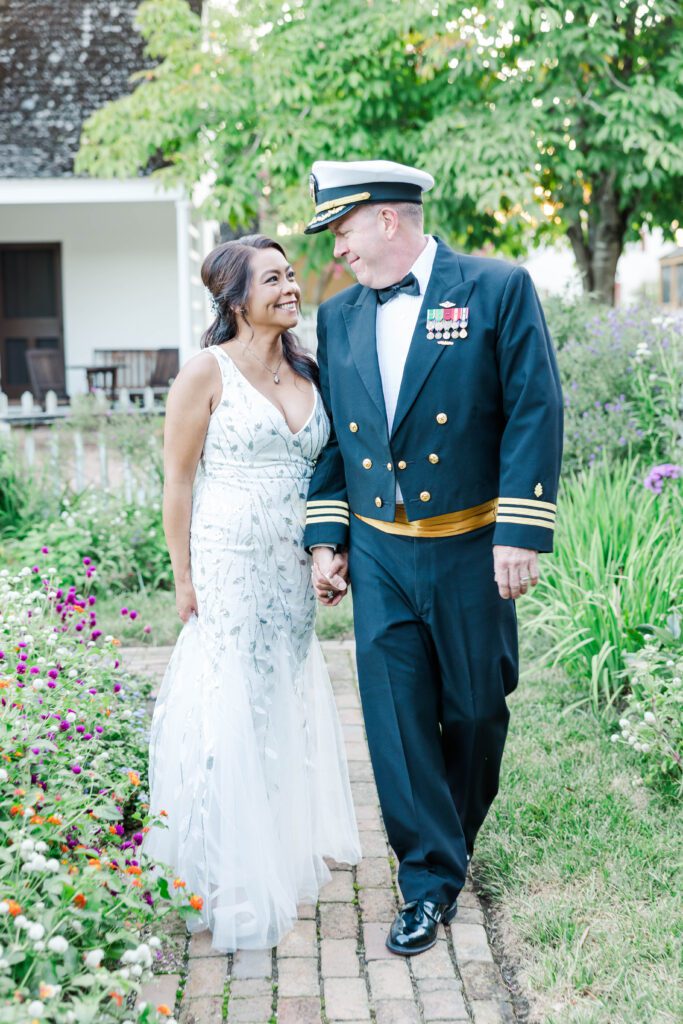couple smiles at each other with garden surrounding them after their Colonial Williamsburg elopement