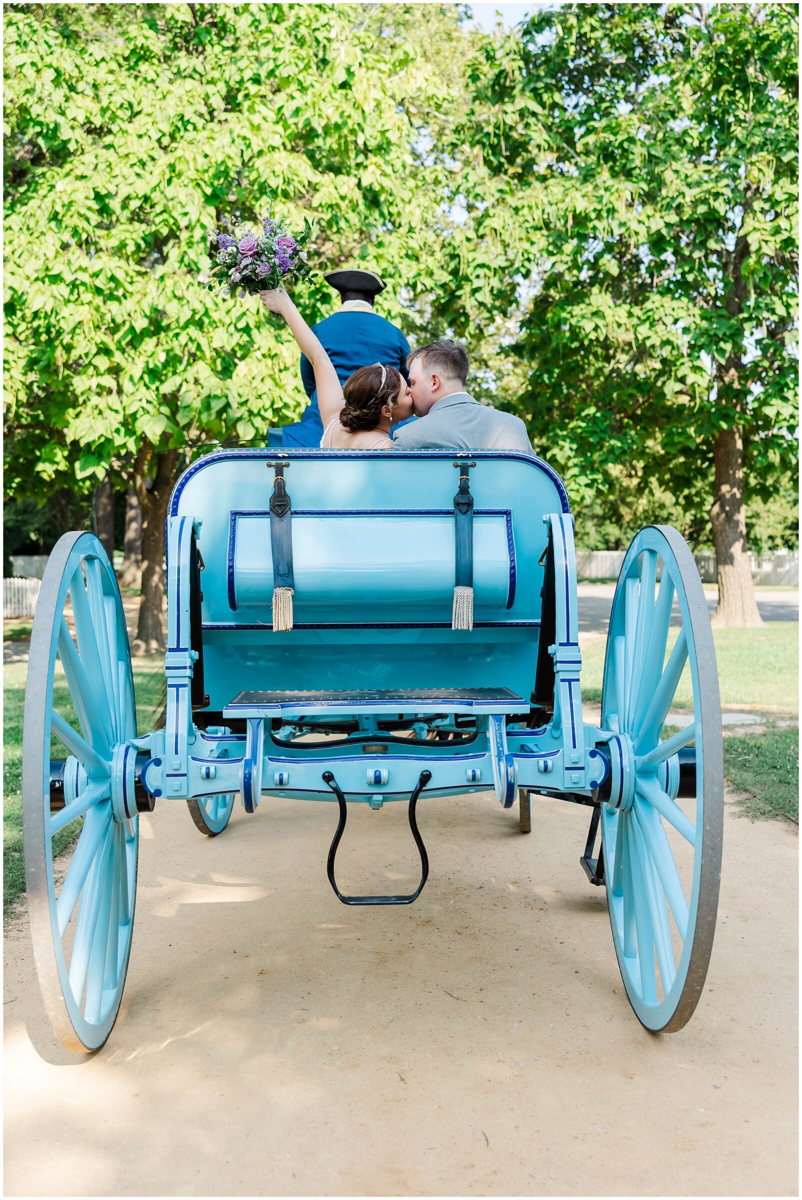 couple celebrates with bouquet in air and horse carriage riding away after choosing from the best wedding photography packages in Williamsburg, VA