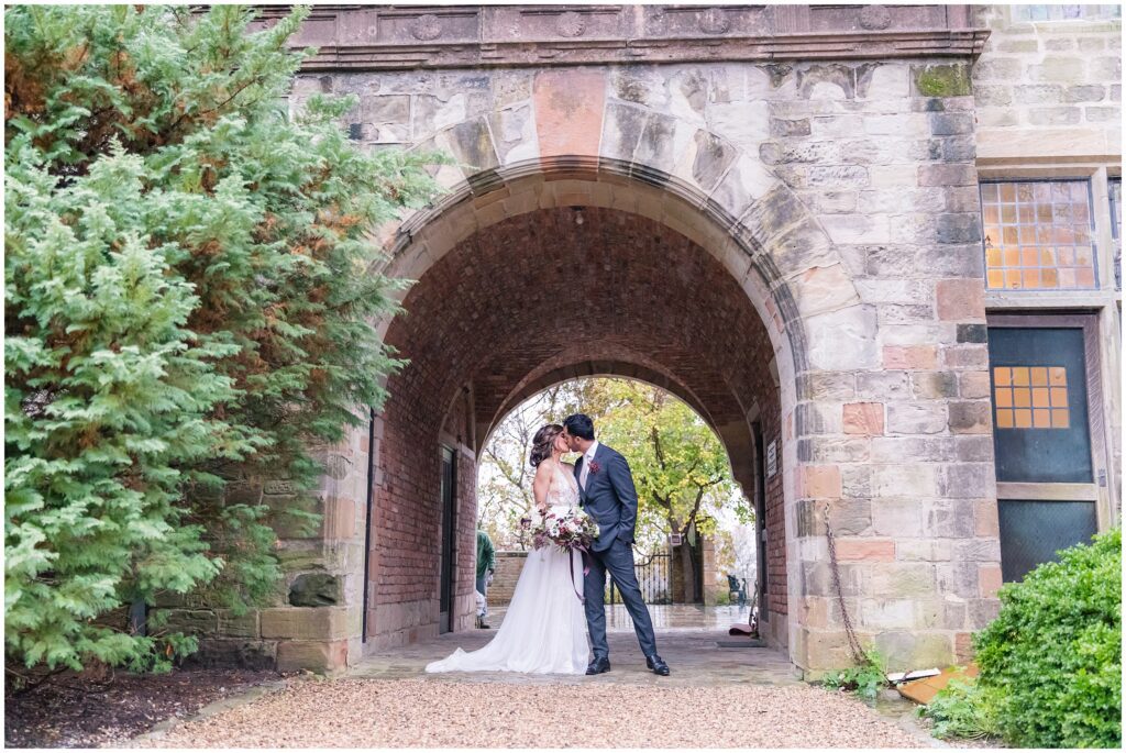 couple kisses under arch of historic Virginia House wedding venue in Richmond, VA