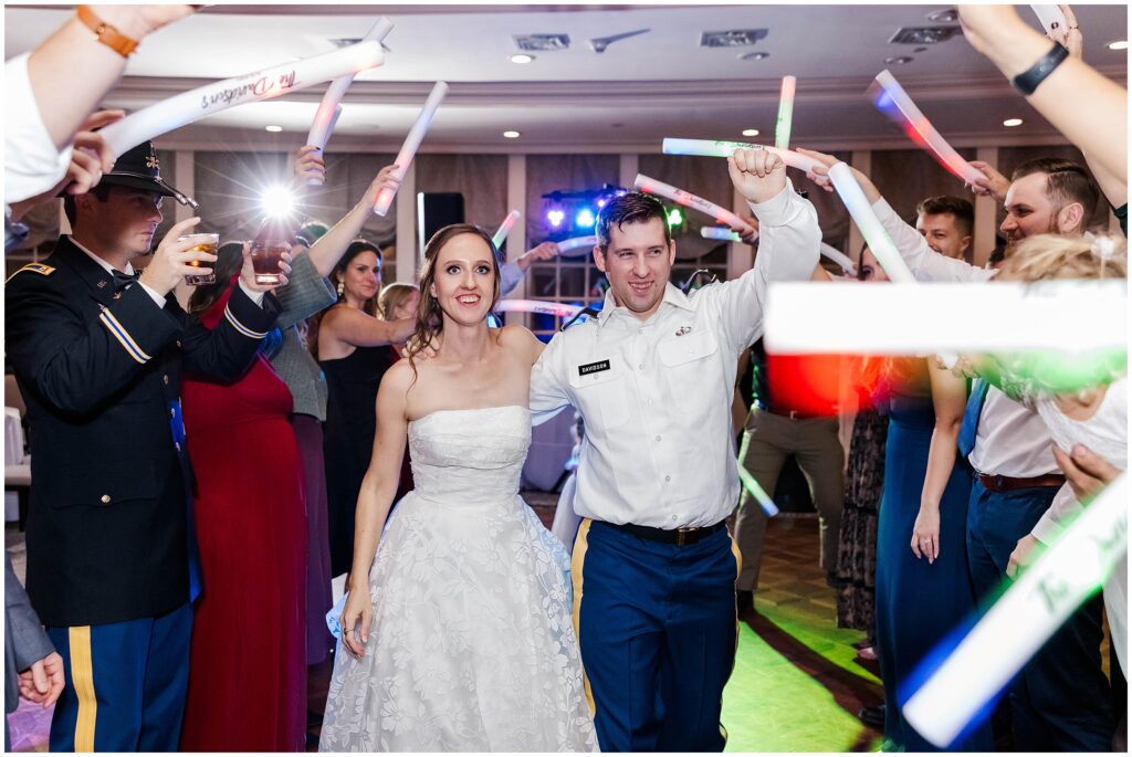 couple walks through glow stick line during wedding reception