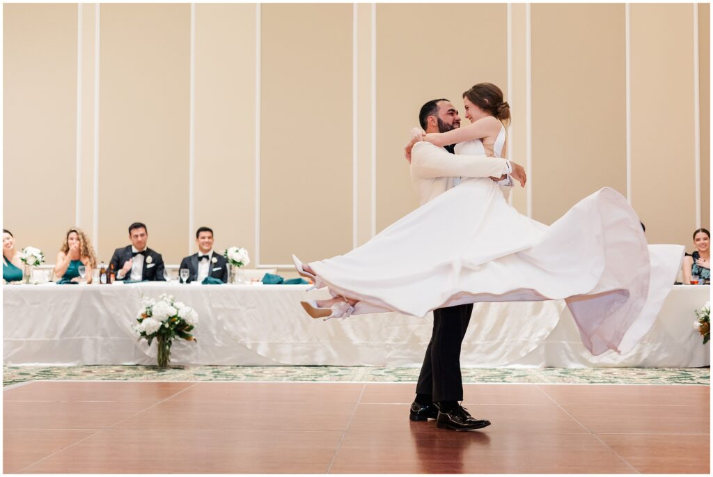 groom swoops bride around with dress flying during dance 