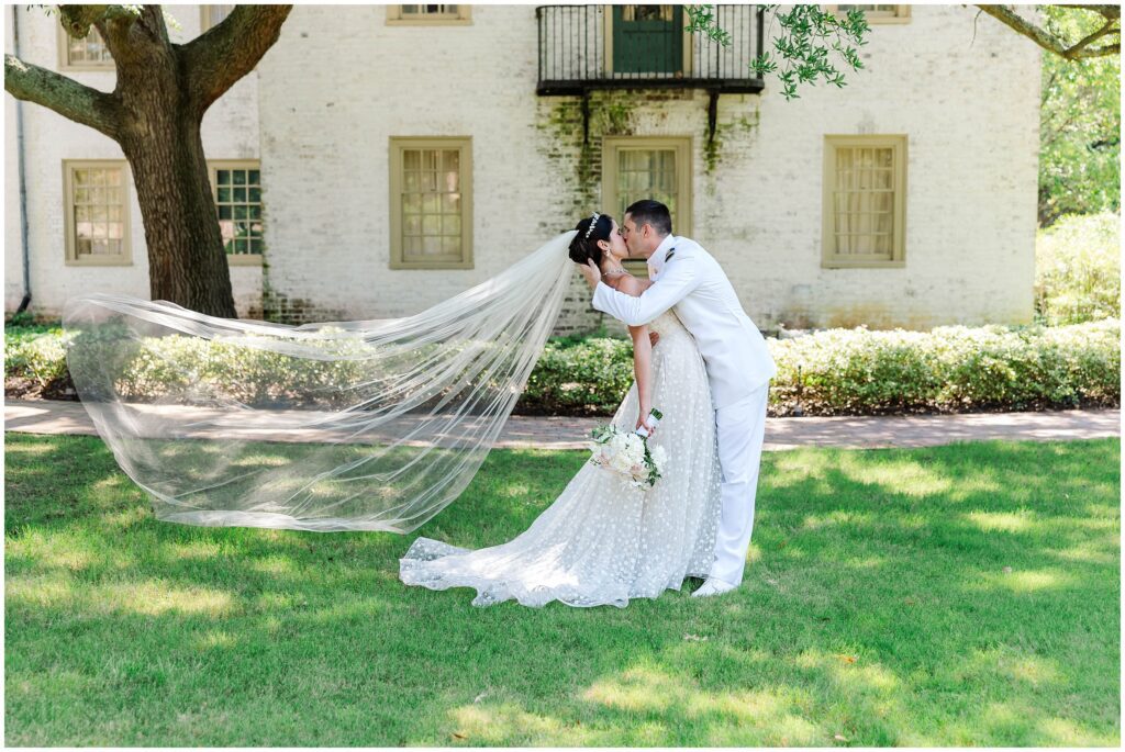 couple dips for a kiss with veil flowing in wind at Williamsburg Inn wedding