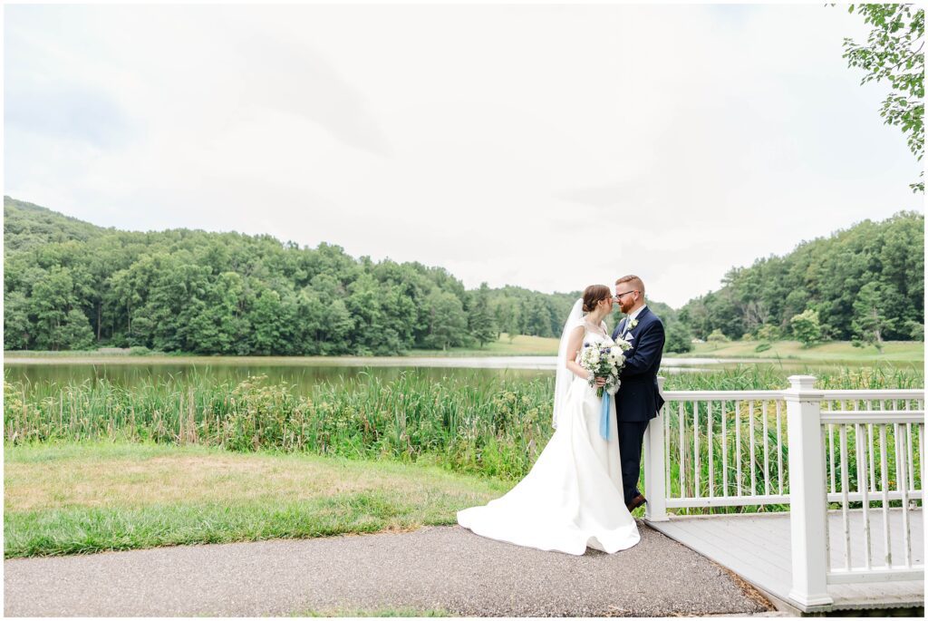 bride and groom by bridge with water in background on overcast rainy wedding day