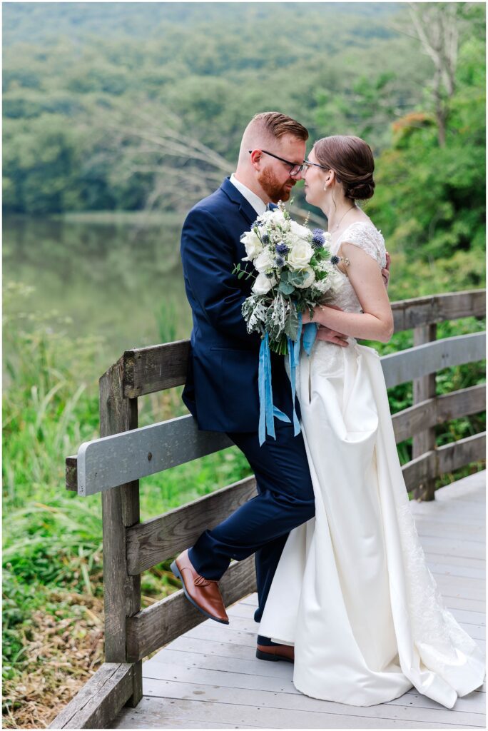 couple gazes into each other's eyes with white and blue bouquet at Peaks of Otter Lodge