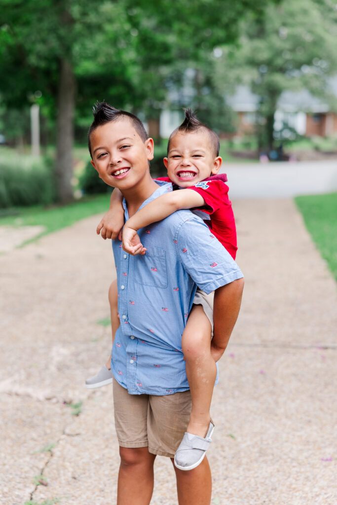 brothers on piggy back smile for photo on first day of school