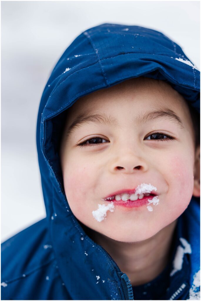 close up of boy playing in snow with snow on face