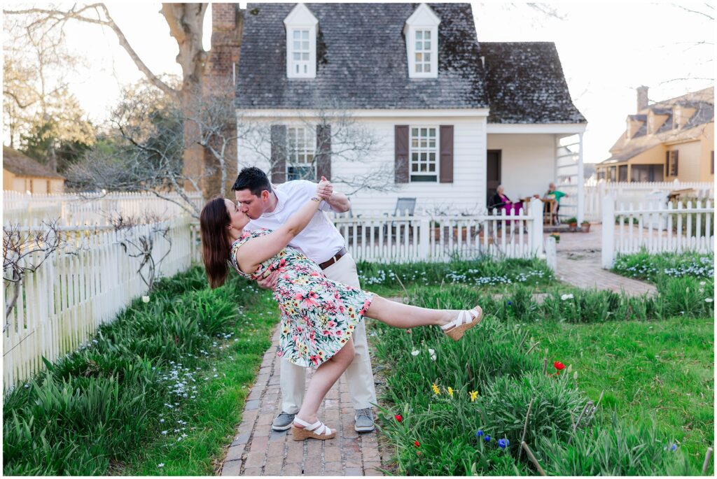 Groom dips bride at engagement session in Colonial Williamsburg garden